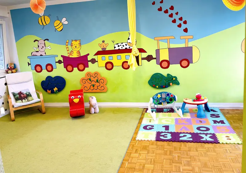 Kącik zabaw z malowanym pociągiem na ścianie i zabawkami do jazdy